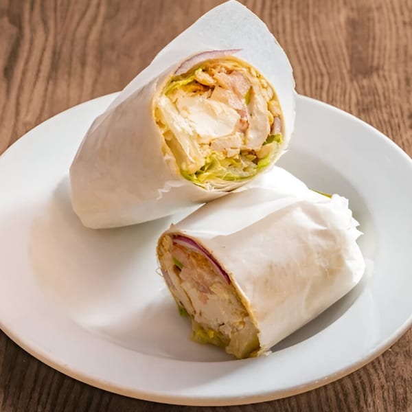 Two chicken wraps, one cut in half, on a white plate at The Bushwick Diner.